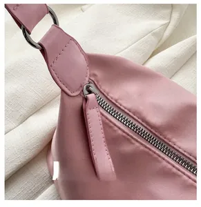 Detail of smooth metal zipper and pink nylon fabric on a lightweight crossbody bag