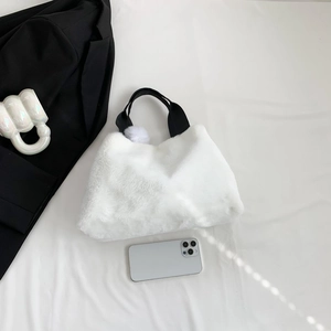Chic white faux fur bucket bag with black handles and a cute fluffy pompom charm