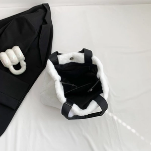White plush tote bag with black strap handles and spacious interior shown from top view