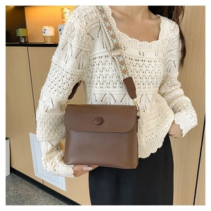 Détail d'un sac bandoulière en cuir marron avec large sangle géométrique style bohème