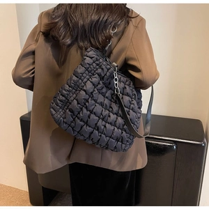 Close-up of black quilted shoulder bag with plush texture and leather strap on model
