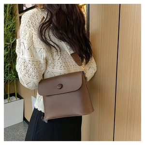 Détail d'un sac bandoulière en cuir marron avec une large sangle en jacquard ethnique