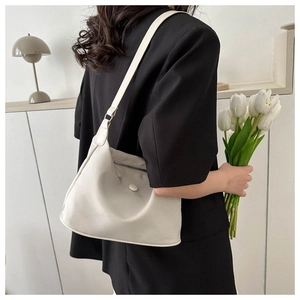 Detail of a beige nylon crescent shoulder bag shown in a minimalist lifestyle setting