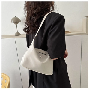 Close-up of minimalist cream crescent shoulder bag with matte leather and metal zipper