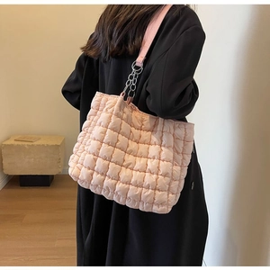 Detail of pink quilted tote bag showing padded fabric texture and metal chain strap