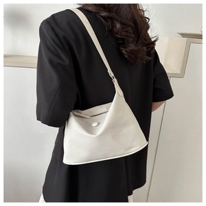 Detail of cream nylon bucket bag worn with a black blazer, showing soft texture and size