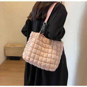 Detail of pink quilted puffer tote bag with metallic chain strap and soft nylon fabric texture