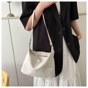 Chic beige nylon shoulder bag with circular detail worn by model in urban outfit