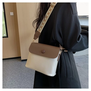 Détail d'un petit sac carré bicolore avec une large bandoulière à motifs géométriques