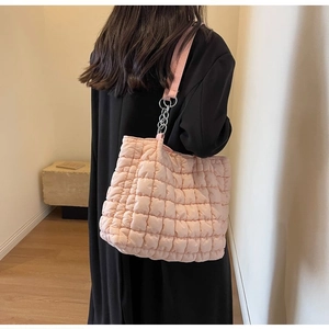 Detailed back view of pink quilted tote bag with chain strap on model in modern room