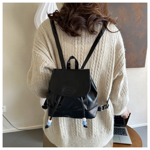 Detalle de la mini mochila de cuero negro minimalista con cordón y logo de moda