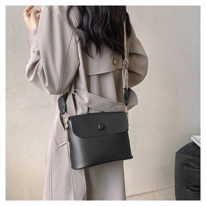 Détail d'un sac bandoulière en cuir mat noir avec une large sangle en jacquard géométrique