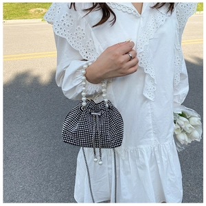 Elegante borsa a secchiello nera con strass e manico di perle su abito in pizzo bianco