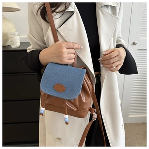 Détail d'un mini sac à dos en similicuir marron et rabat en jean avec étiquette FASHION