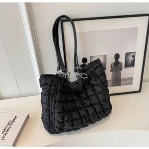 Detail view of the quilted bubble texture and sleek silver hardware on this black tote bag