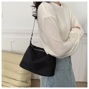 Side view of minimalist black nylon shoulder bag shown on model for casual styling