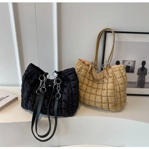 Detail of quilted puffy tote bags in black and beige with metallic chain link straps