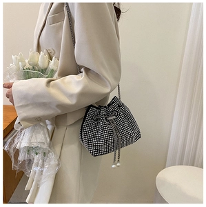 Dettaglio della borsa a secchiello in strass con tracolla a catena e coulisse di perle