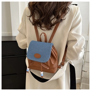 Détail du mini sac à dos en jean et cuir montrant les textures et l'étiquette mode