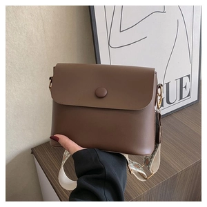Détail d'un sac à bandoulière marron avec sangle géométrique et boucle ronde décorative