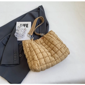 Detail of khaki quilted bubble tote bag with leather straps and silver metal chain links