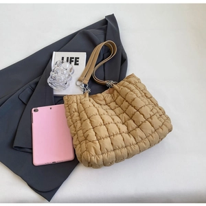 Detail of beige quilted puffer tote bag showing textured square pattern and interior space