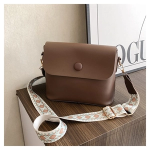 Détail d'un sac bandoulière vintage marron avec bandoulière tissée aux motifs ethniques