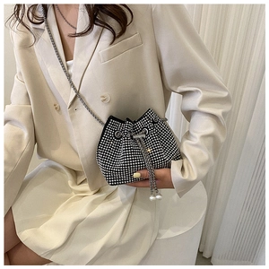 Dettaglio di una borsa a secchiello nera con strass, catena argento e chiusura a coulisse