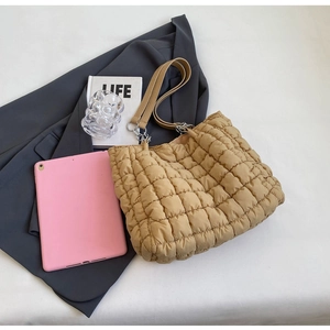 Top view of a khaki quilted bubble tote bag next to a tablet and grey blazer