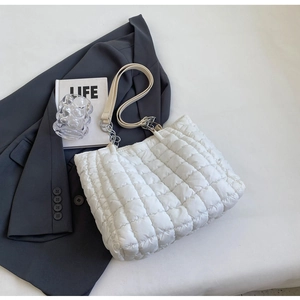 Detail of white quilted puffer tote bag with silver chain strap on blue blazer