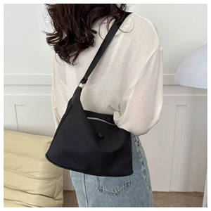 Black waterproof nylon hobo bag shown on shoulder in a modern minimalist home setting
