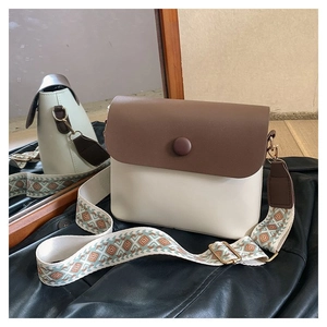 Détail du sac bandoulière contrasté avec rabat marron et large sangle à motifs