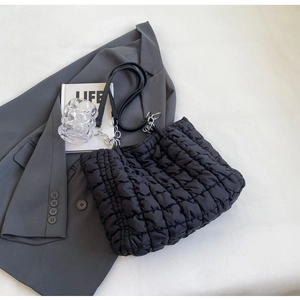 Detail of black quilted tote bag texture with silver chain and leather shoulder strap