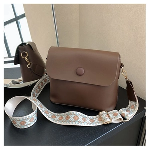 Détail d'un sac bandoulière vintage en cuir marron avec sangle tissée géométrique