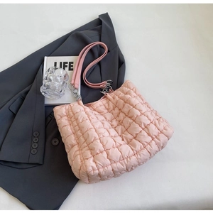 Close-up of pink quilted tote bag with silver chain strap on grey blazer