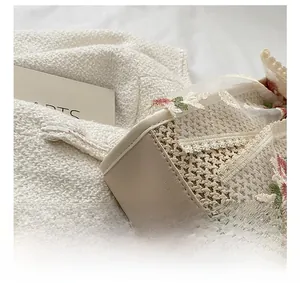 Detailed close-up of straw beach bag with pink floral lace embroidery and PU leather stitching