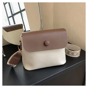 Détail du sac à bandoulière bicolore avec sangle géométrique large et bouton décoratif