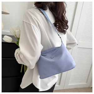 Close-up of light blue waterproof nylon shoulder bag worn over a white shirt
