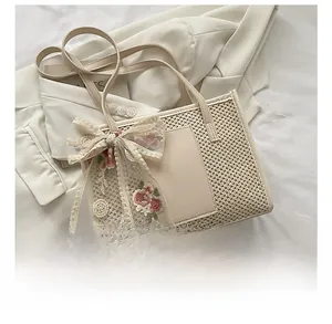 Straw tote bag detail with lace embroidery bow and synthetic leather handles on white blazer