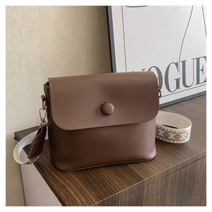 Détail du sac en cuir marron avec bandoulière brodée ethnique et finition en cuir mat