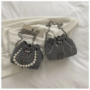 Dettaglio di una borsa a secchiello nera con strass argento e manico di perle
