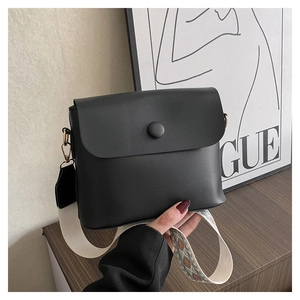 Détail d'un sac bandoulière noir avec large sangle brodée et finitions dorées chic