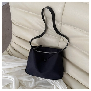 Close-up of lightweight black nylon shoulder bag with silver zipper on a beige sofa