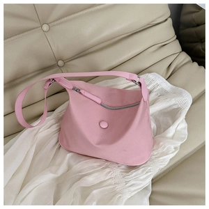 Detail of a pink nylon crossbody bag on a beige leather sofa with soft white tulle