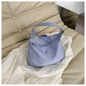 Close-up of light blue nylon shoulder bag with zipper and round decorative buckle