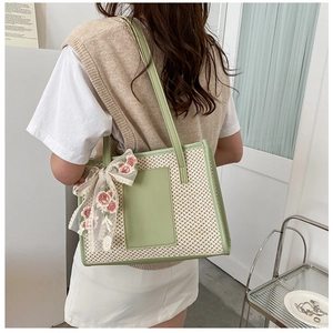 Detail of straw woven beach tote bag with green leather trim and pink floral lace bow