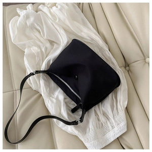 Black nylon crescent bag with silver zipper on white shirt and beige sofa