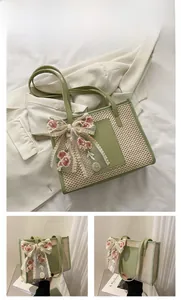 Detail of green straw tote bag featuring mesh bow and pink flower embroidery