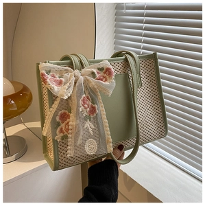 Detail of hand-woven beach tote with lace bow and pink floral embroidery accents