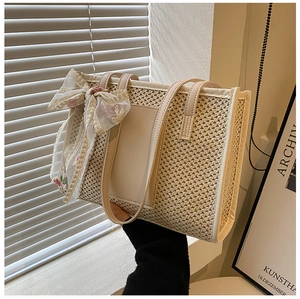 Detail of beige straw tote bag with cream leather edges and floral lace bow accent
